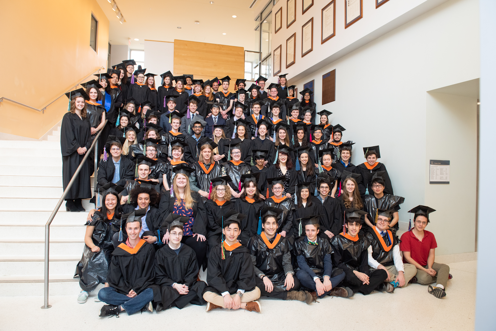 A group photo of people wearing graduation caps and gowns, some of which appear to be homemade.