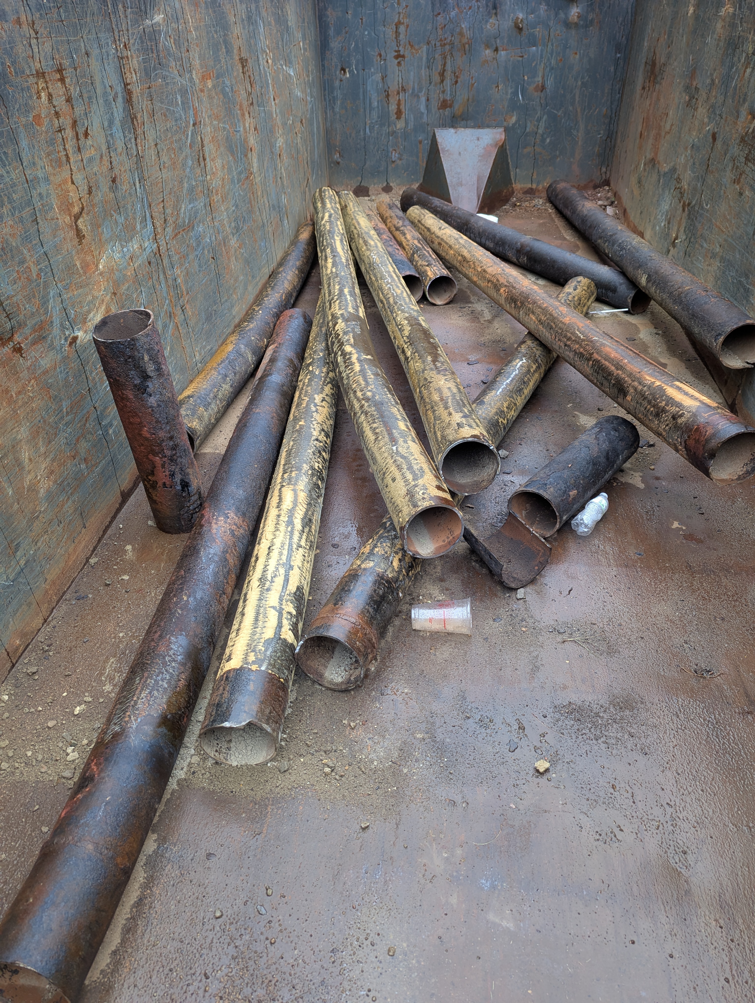 Old pipe to be recycled. Note the small pipe section standing up-on-end.