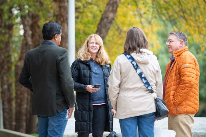 A photo of four people talking to on another outside