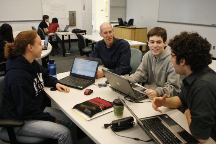 A scene from a data science class at Olin College of Engineering A photo of a group of people in a classroom sitting at a table with laptops