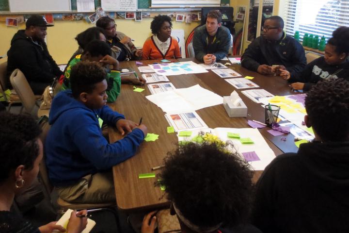 A photo of a group of people, college students and high schoolers co-creating a curriculum