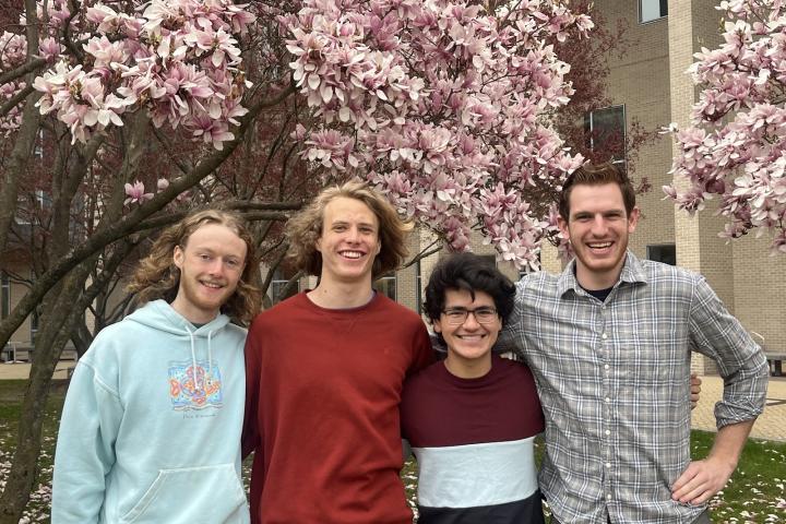 Four students in front of blooming trees