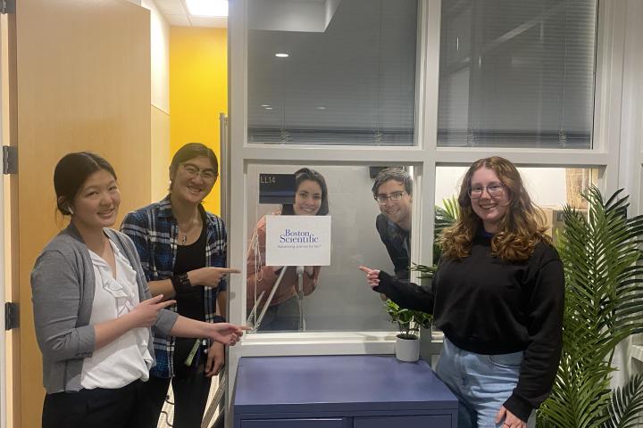 Five students pointing to a sign for Boston Scientific