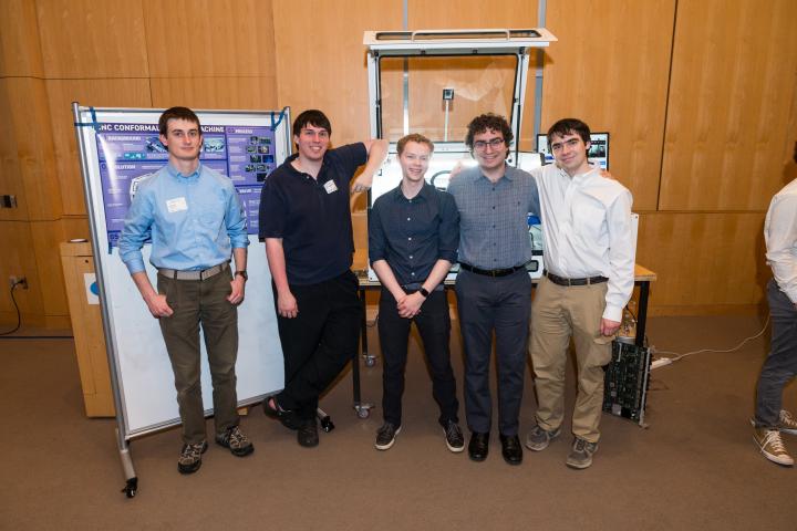 Students posing in front of project poster at Summit