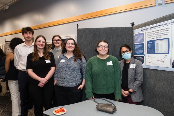 Students posing in front of project poster at Summit