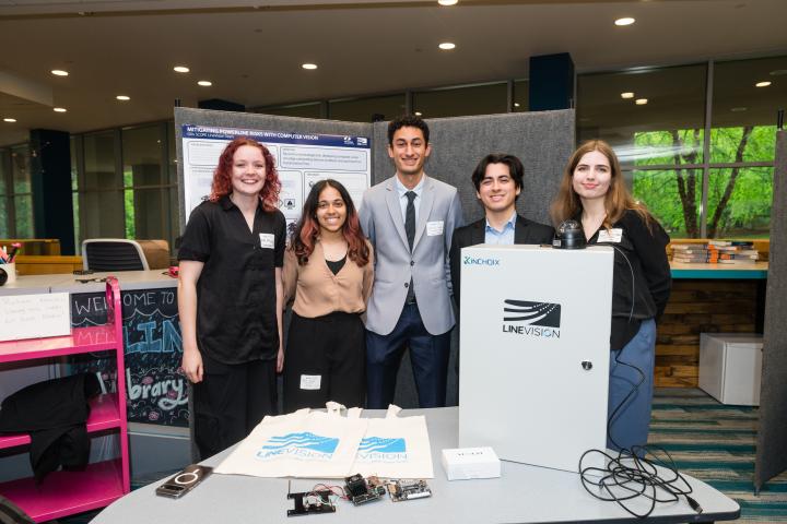 Students posing in front of project poster at Summit