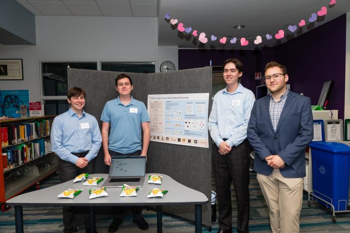 Students posing in front of project poster at Summit