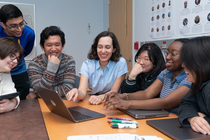 Professor Andrea Cuadra and Students Professor Andrea Cuadra gathered around a computer with her students