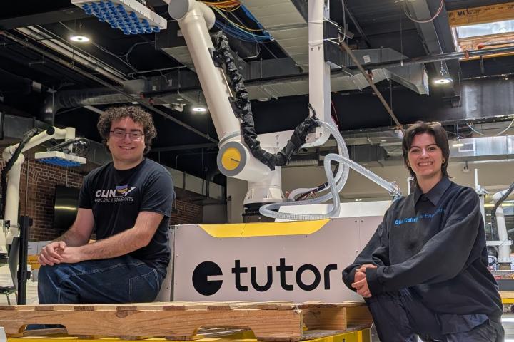 Olin College alums Ellie Ramos ’25 and Jacob Prisament ’25 pose with a Tutor Intelligence Robot