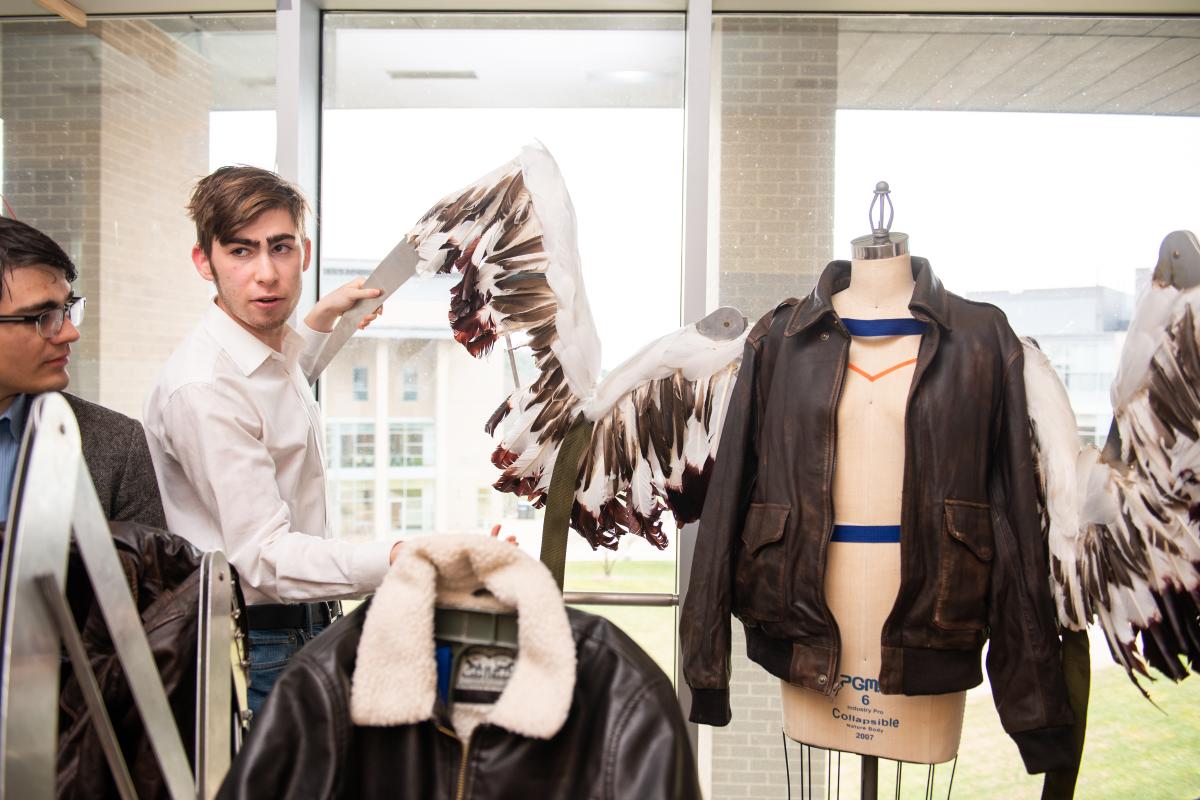 A photo of a person holding up what looks like a wing that has been fabricated as part of a brown leather jacket