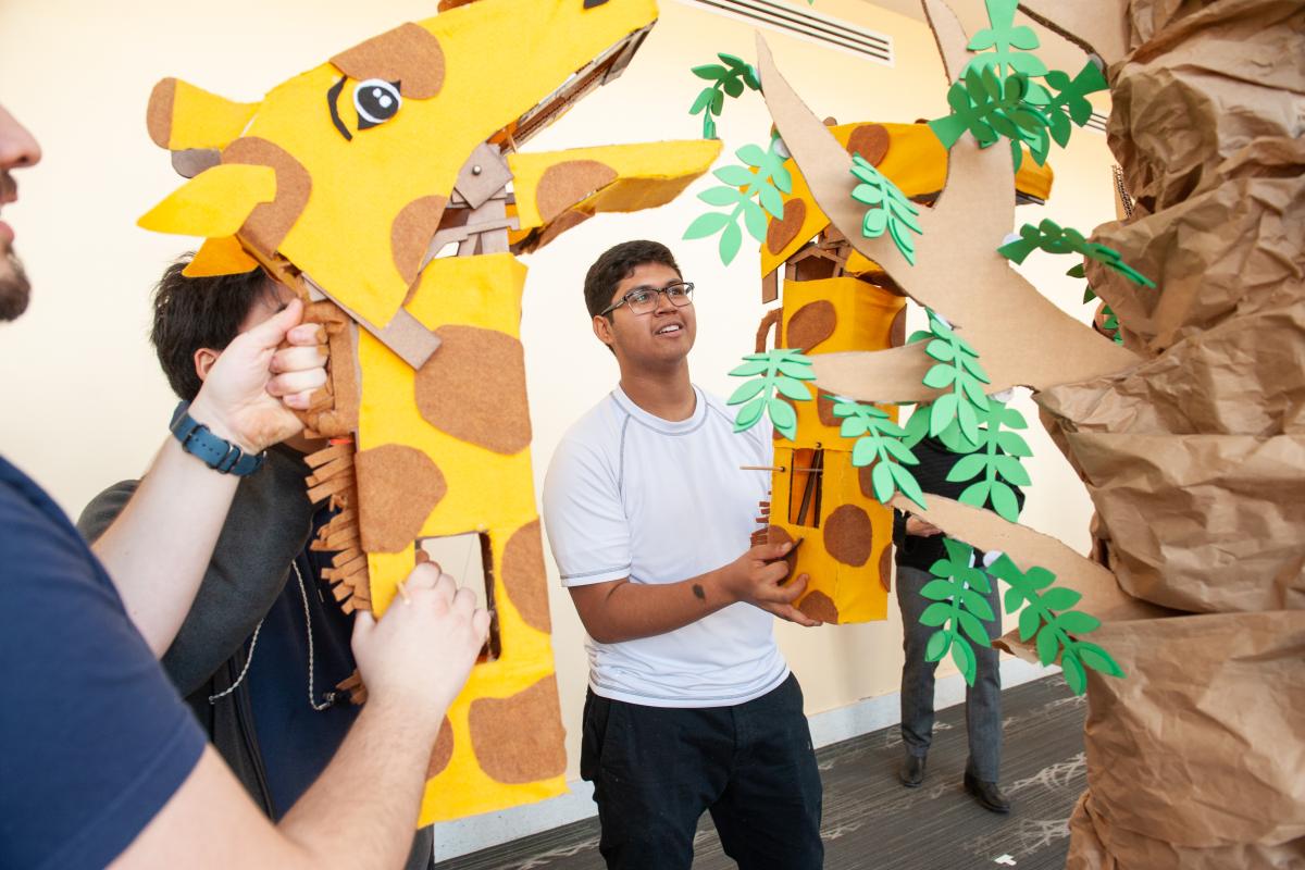 A photo of a man using a giraffe head to play a game