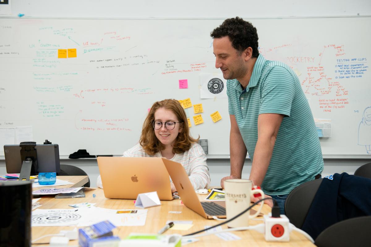 Professor Paul Ruvolo works with a student on a Summer Research project A photo of a professor and a student in a classroom looking at a laptop computer