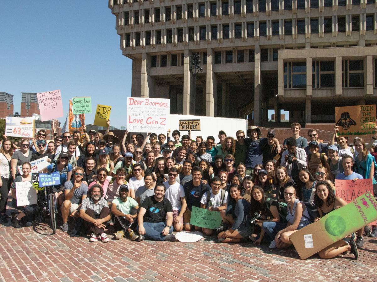 A large group of people gather and hold signs at a climate protest in Boston, MA. 