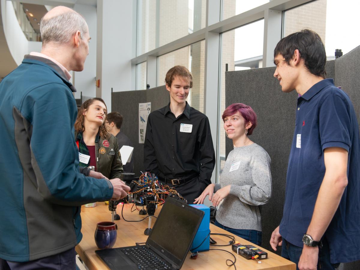 RoboLab students present their hexapod at Fall Expo 2019 Three students behind a table present their hexapod to another person at Fall Expo 2019