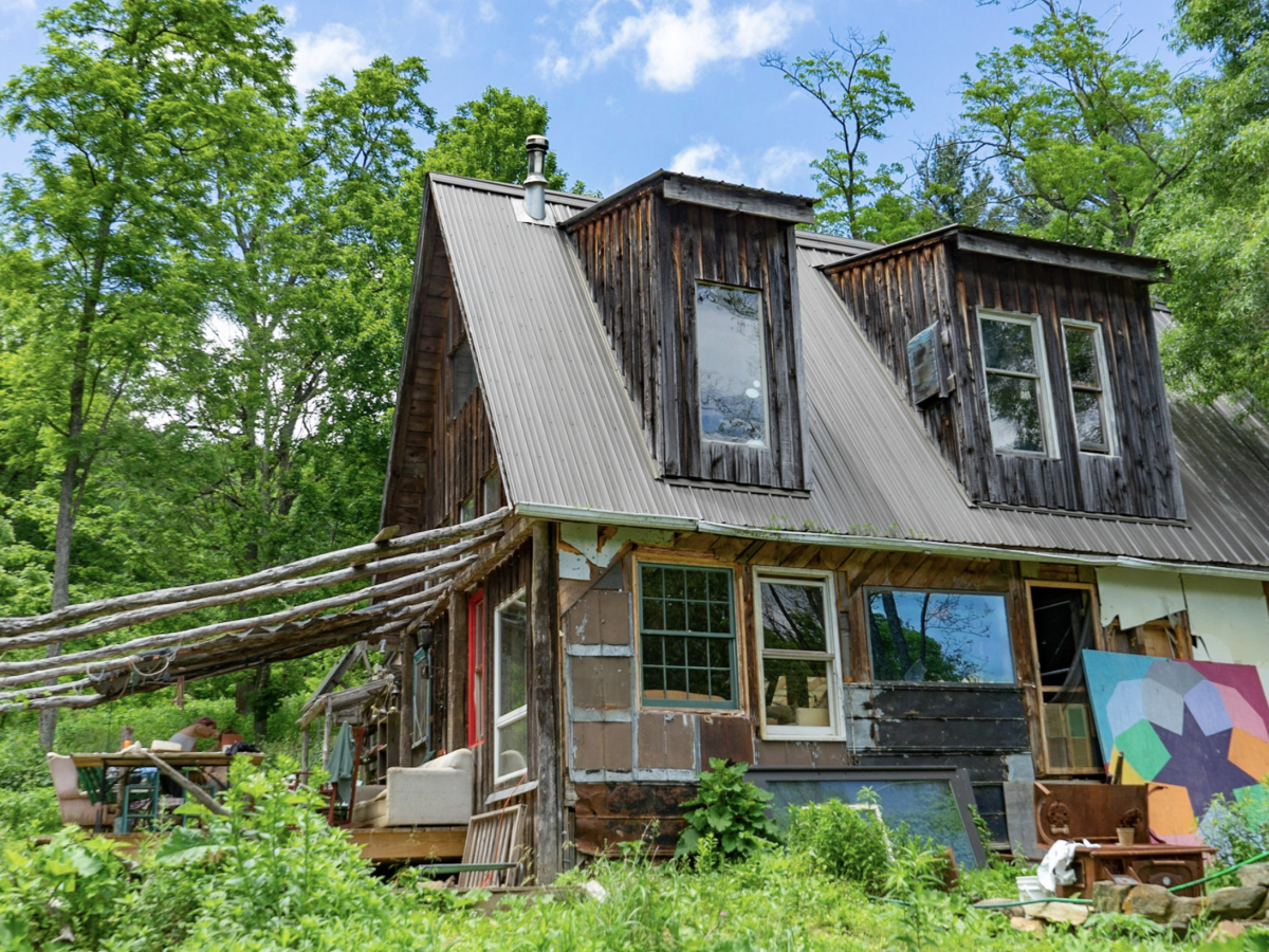A house on Woodland Harvest Farm in NC A brown house surrounded by green foliage as part of the larger Woodland Farms