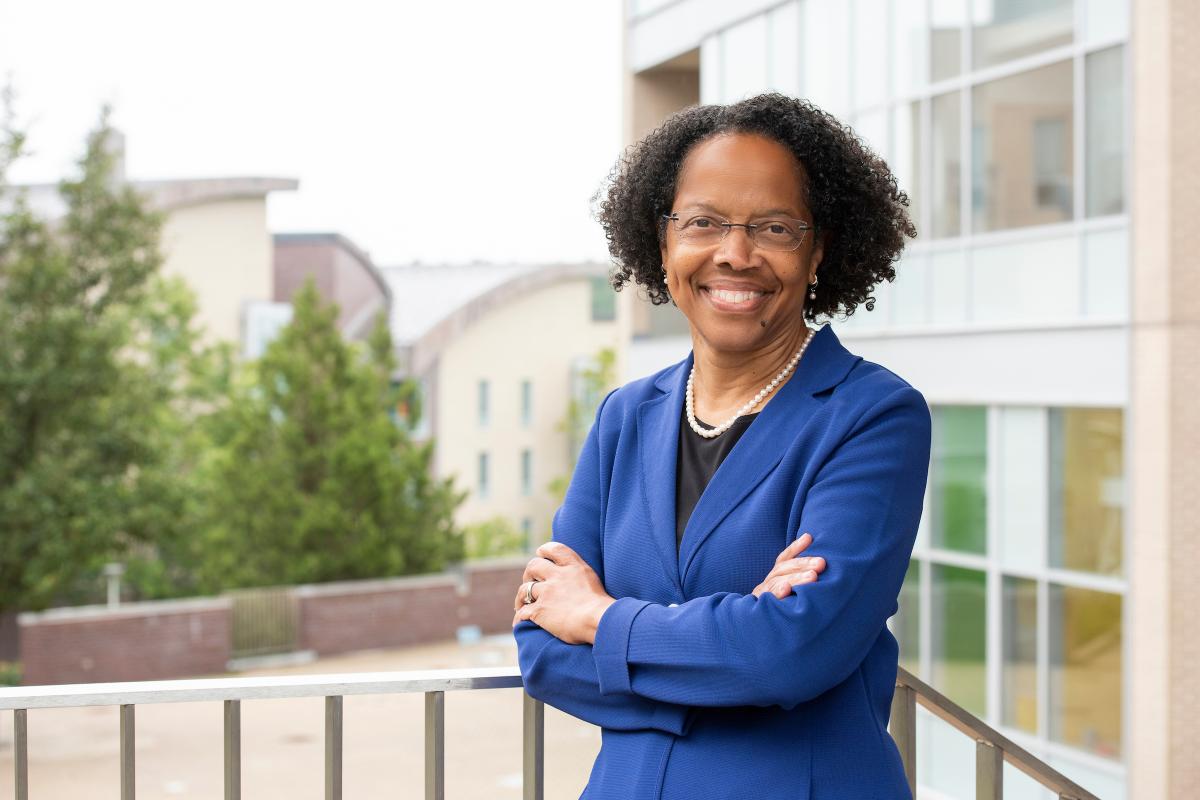 Dr. Gilda A. Barabino, President of Olin College of Engineering. Dr. Gilda A. Barabino, Olin College of Engineering President, smiles and poses outside with trees in background, with arms crossed while wearing a royal blue blazer.