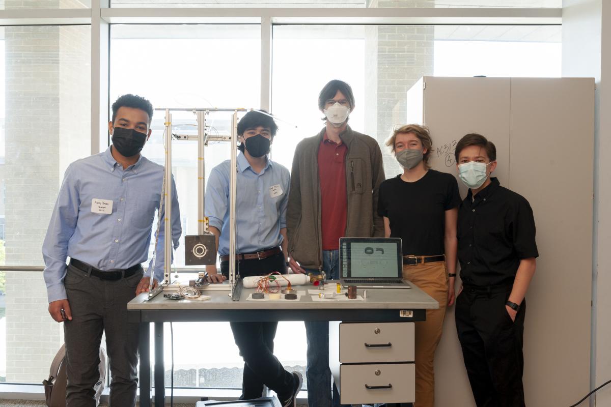 Members of Braden Oh's '23 Expo presentation team gather around a table with the thruster.