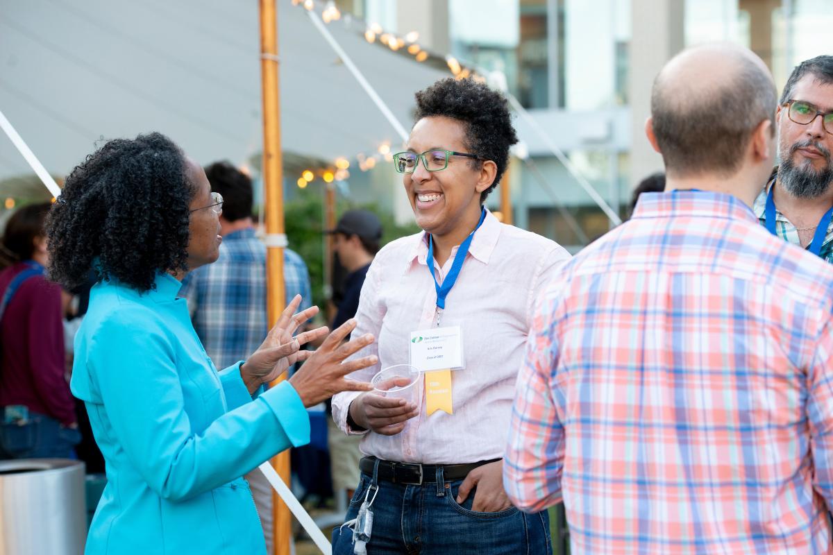 Two people share a conversation together during an outside cocktail party.