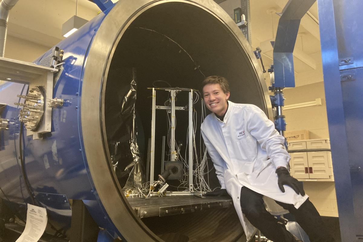 Olin student Braden Oh '23 leans against a large circular opening in the MIT Space Propulsion Lab. Olin student Braden Oh '23 leans against a large circular opening in the MIT Space Propulsion Lab.