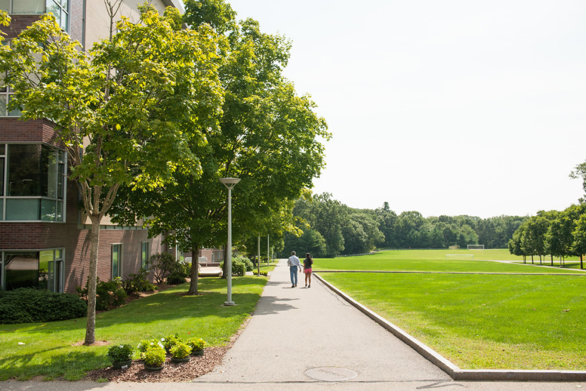 two people walking along sidewalk between west hall and great lawn on a sunny day