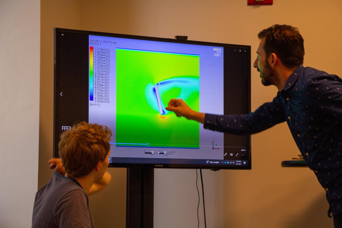 Professor Ivo Nedyalkov points to the computer screen during a recent co-curricular in Spring 2023. A man points to a glowing green computer screen while a student looks on.