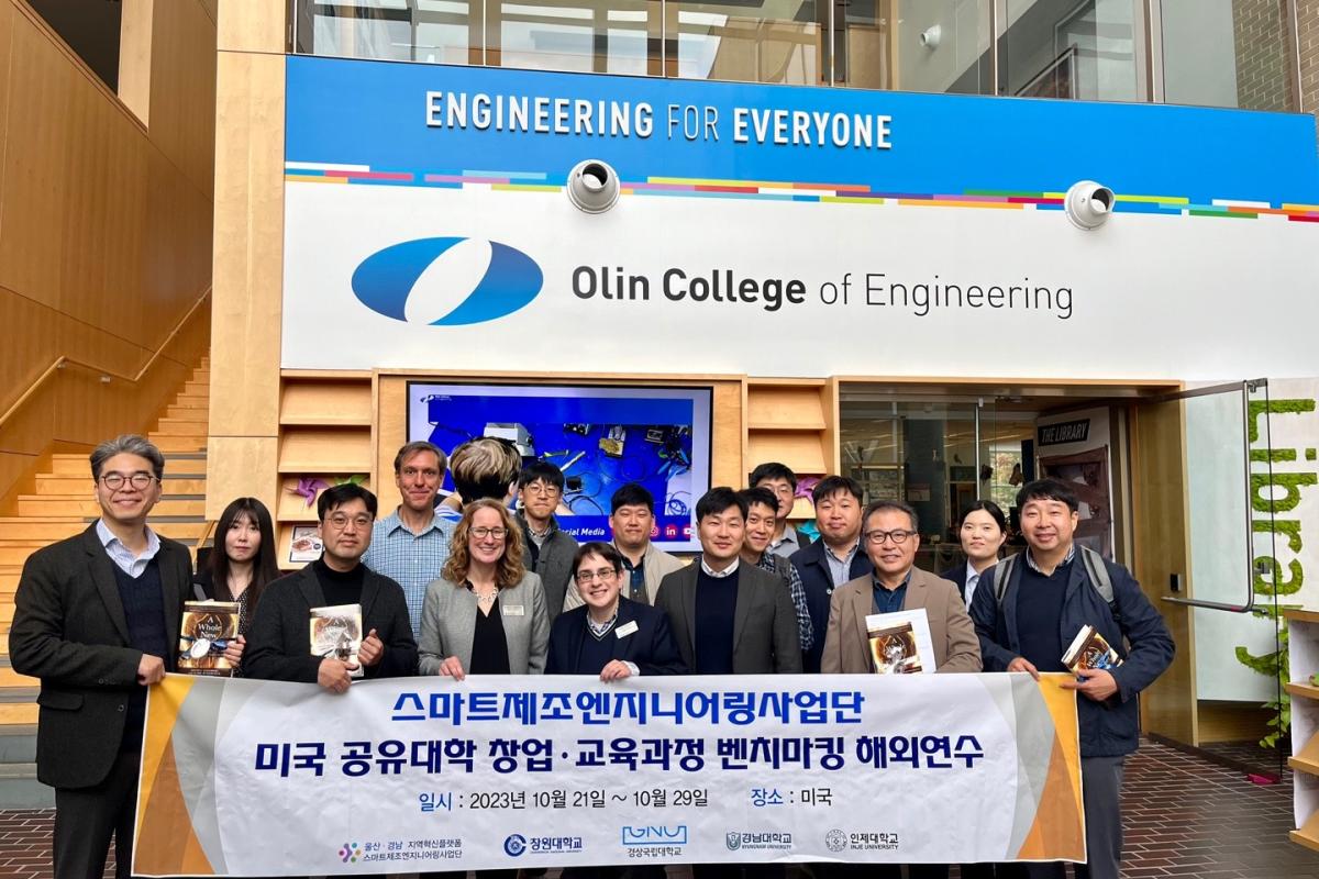 Visitors and Olin faculty holding a banner