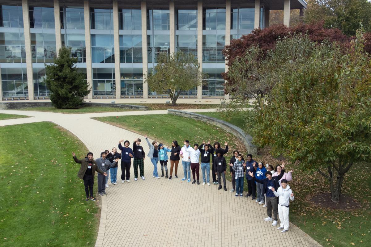 Group of students in the OVAL greenspace waving for a drone photo