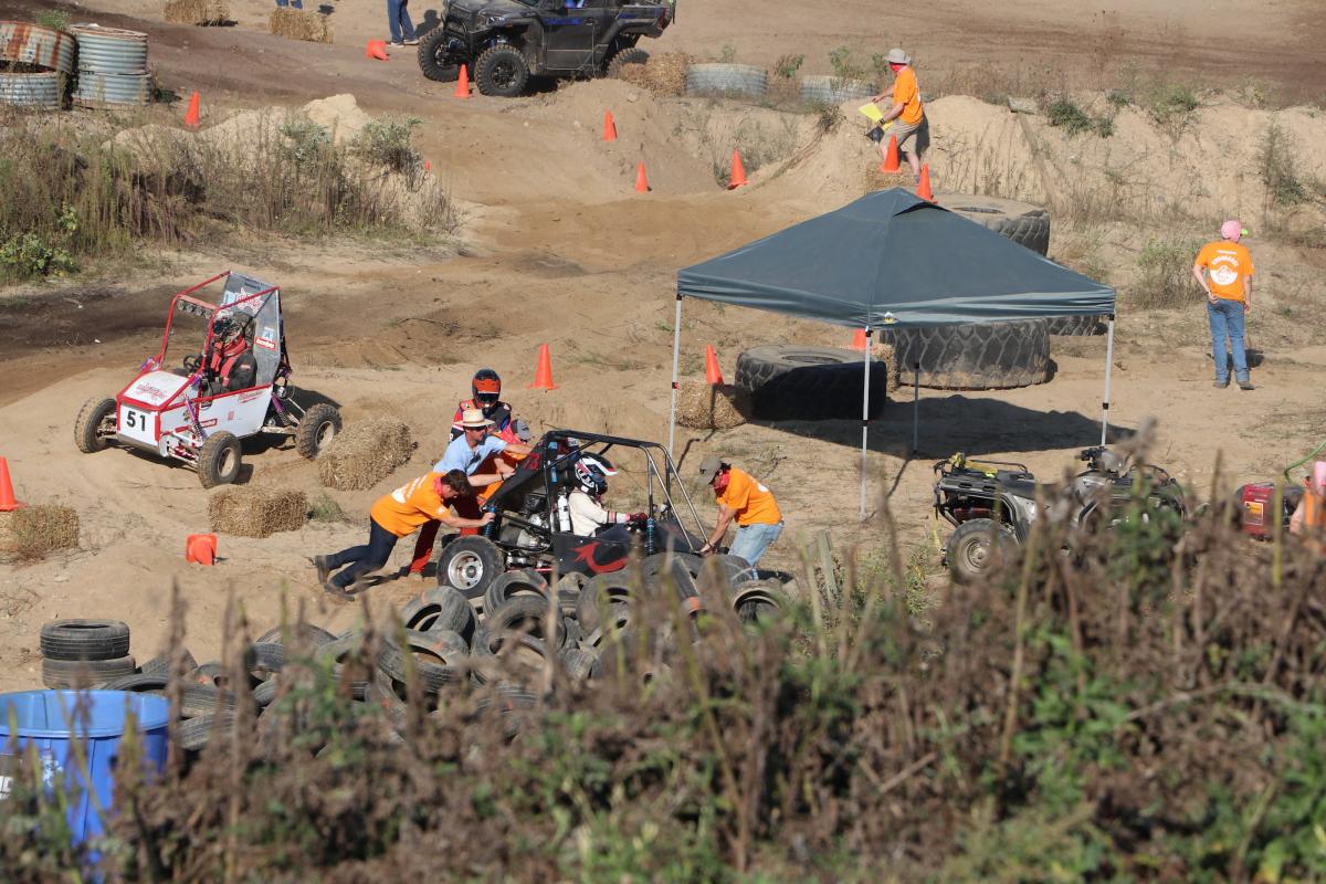 An off-road Baja vehicle is seen being pushed through some sand mounds on a track. An off-road Baja vehicle is seen being pushed through some sand mounds on a track.