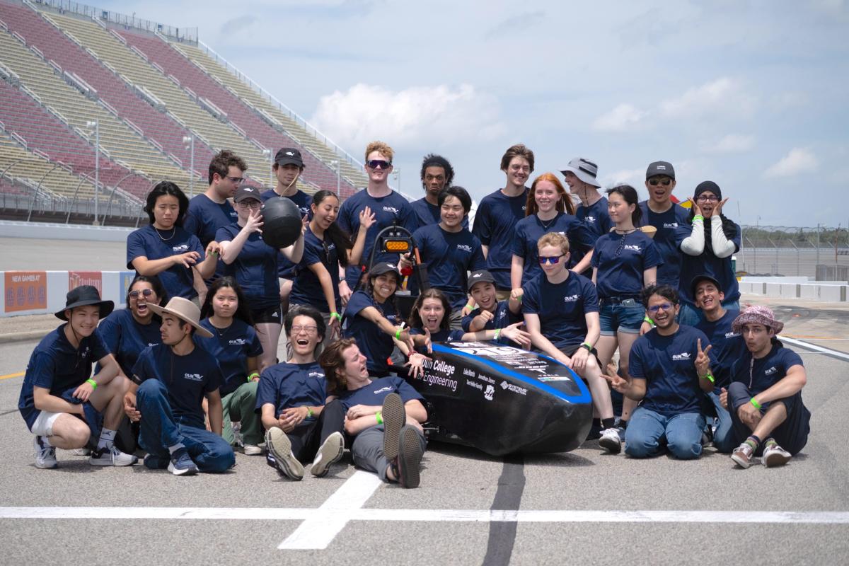 The Olin Electric Motorsports team pose with their car at the Formula SAE Electric competition in 2024.