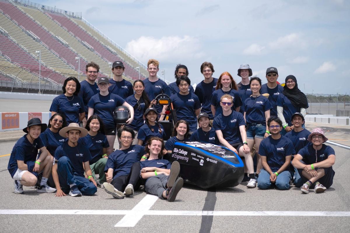 The Olin College of Engineering student project team Olin Electric Motorsports (OEM) pose for a group photo on the race track at a competition this summer.
