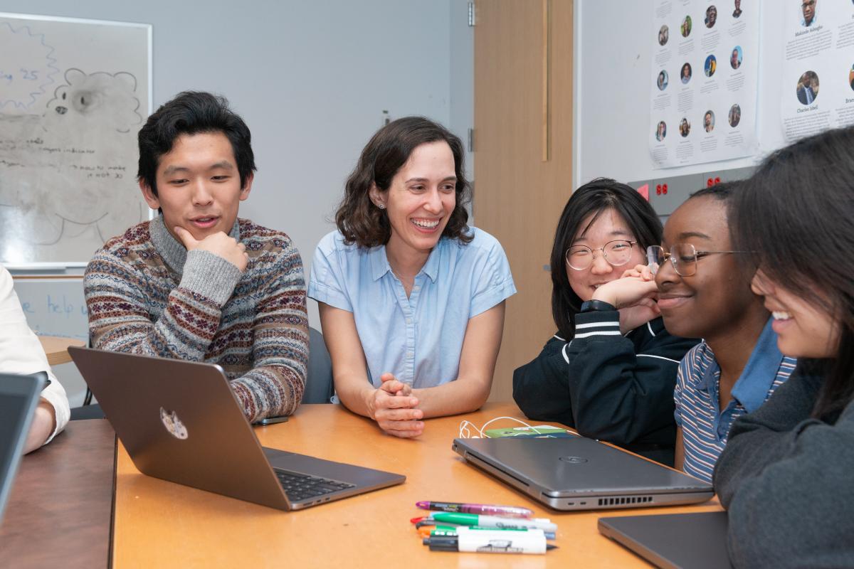 Students gather around a laptop with Andrea Cuadra ’13, Assistant Professor of Computer Science, who wears the light blue shirt. Students gather around a laptop with Andrea Cuadra ’13, Assistant Professor of Computer Science, who wears the light blue shirt.