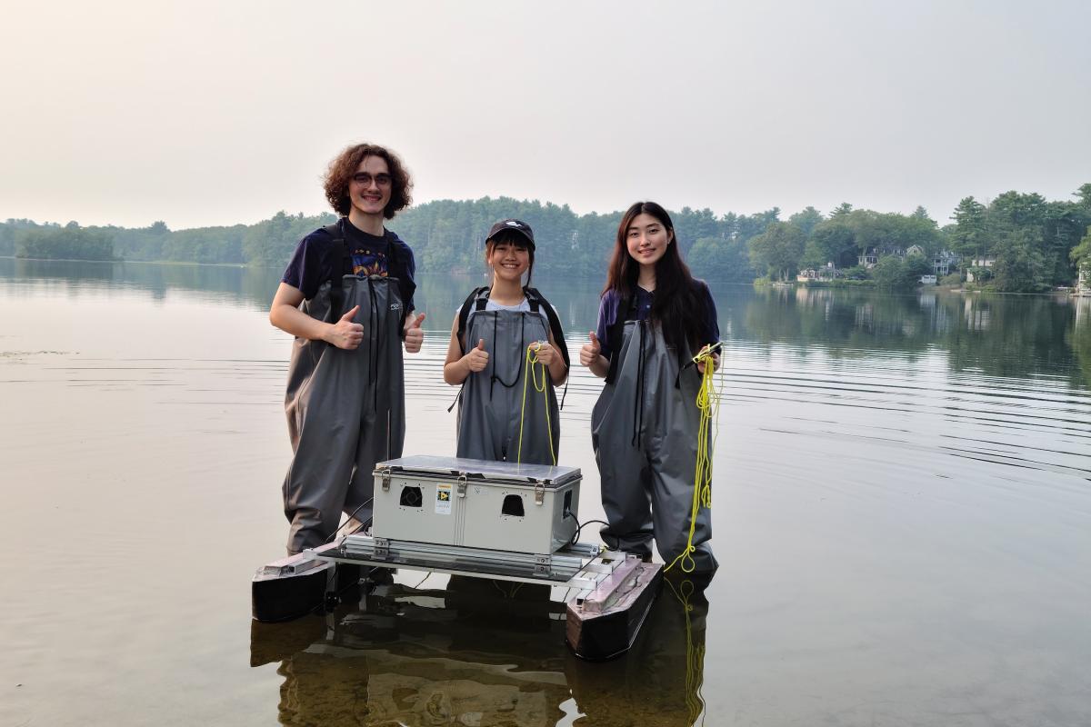 Three CREST Lab researchers pose with their boat in shallow water.