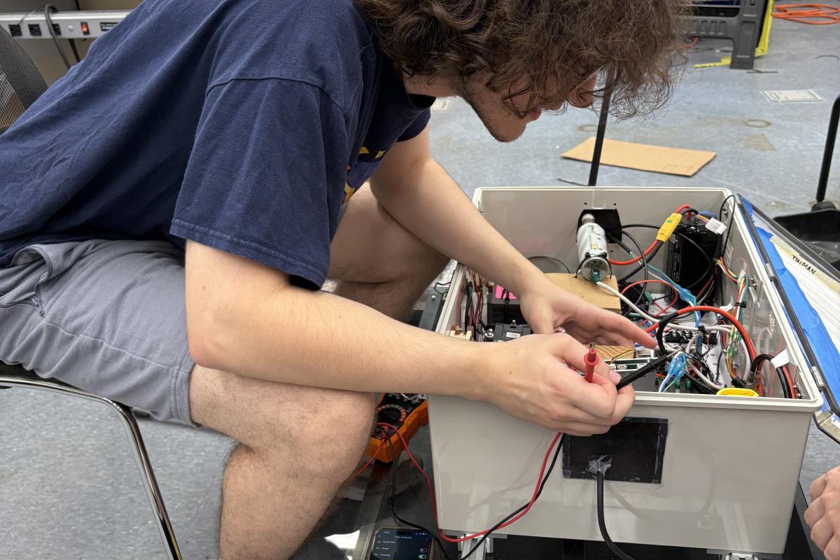 Enzo Smajlaj ’28, an electrical and computer engineering major, is seen wiring and integrating the electrical box and enclosure that'll allow their boat to move.