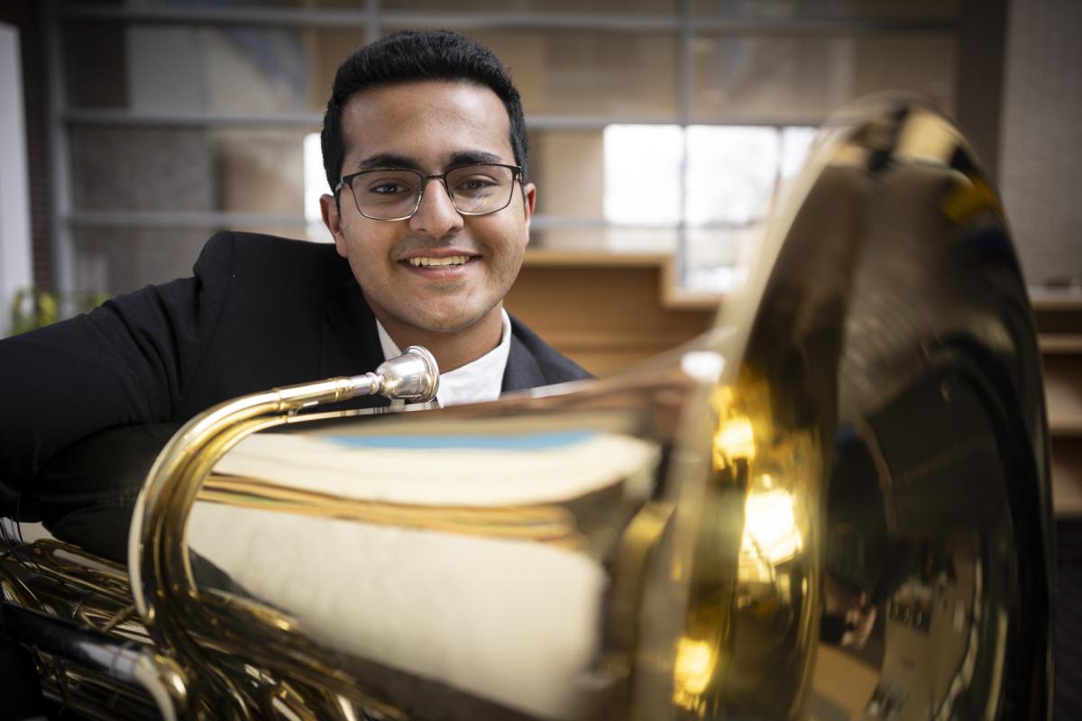 An OCO student musician smiles at the camera while holding their instrument. 