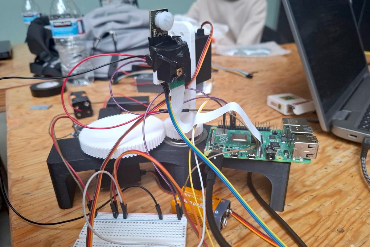 The computer-vision–powered laser turret concept, AuruShield, is shown on a desk.