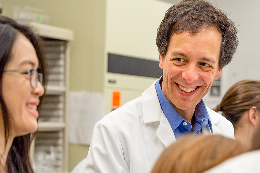 A photo of Rob Martello in a lab coat talking to a student