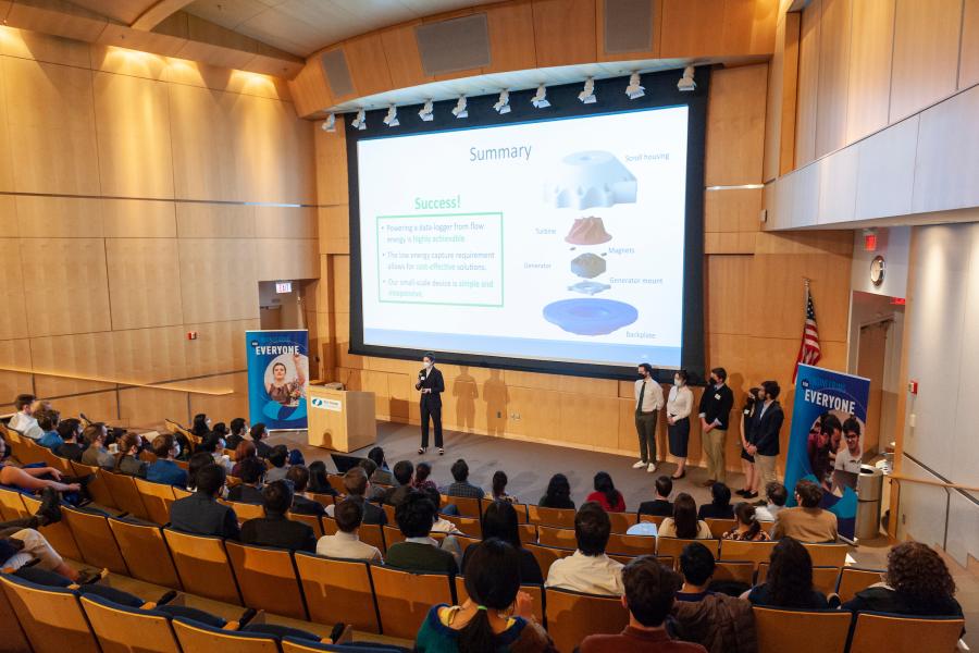 SCOPE Summit 2022a Student presenting in auditorium with slides