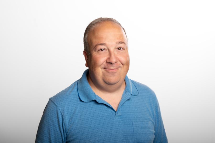 Portrait of Brian Krongold, wearing a checkered blue polo smiling at camera