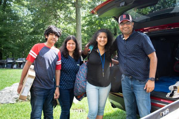 A photo of a family of four posing outside on move-in day for college