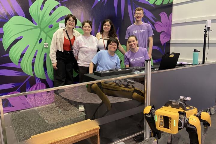 Oliners gather around the robot at the RAI Institute. 