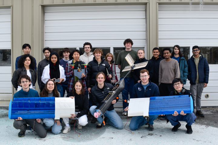 A group photo of of Olin's AERO team with members holding an electric RC Aircraft, its Wings, and Controller