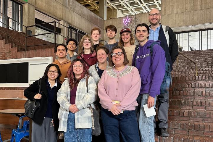 A group of over 10 students and professionals stand for a group photo at Boston City Hall. 