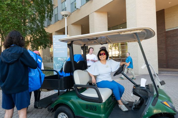 A volunteer at Olin's 2025 move in rests at the wheel of a campus shuttle