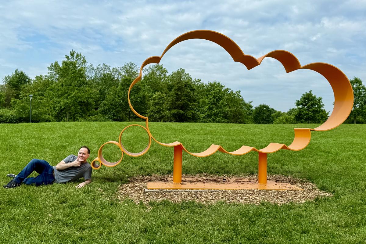 Jonathan Adler poses next to a thought bubble sculpture in a field. Jonathan Adler poses next to a thought bubble sculpture in a field.