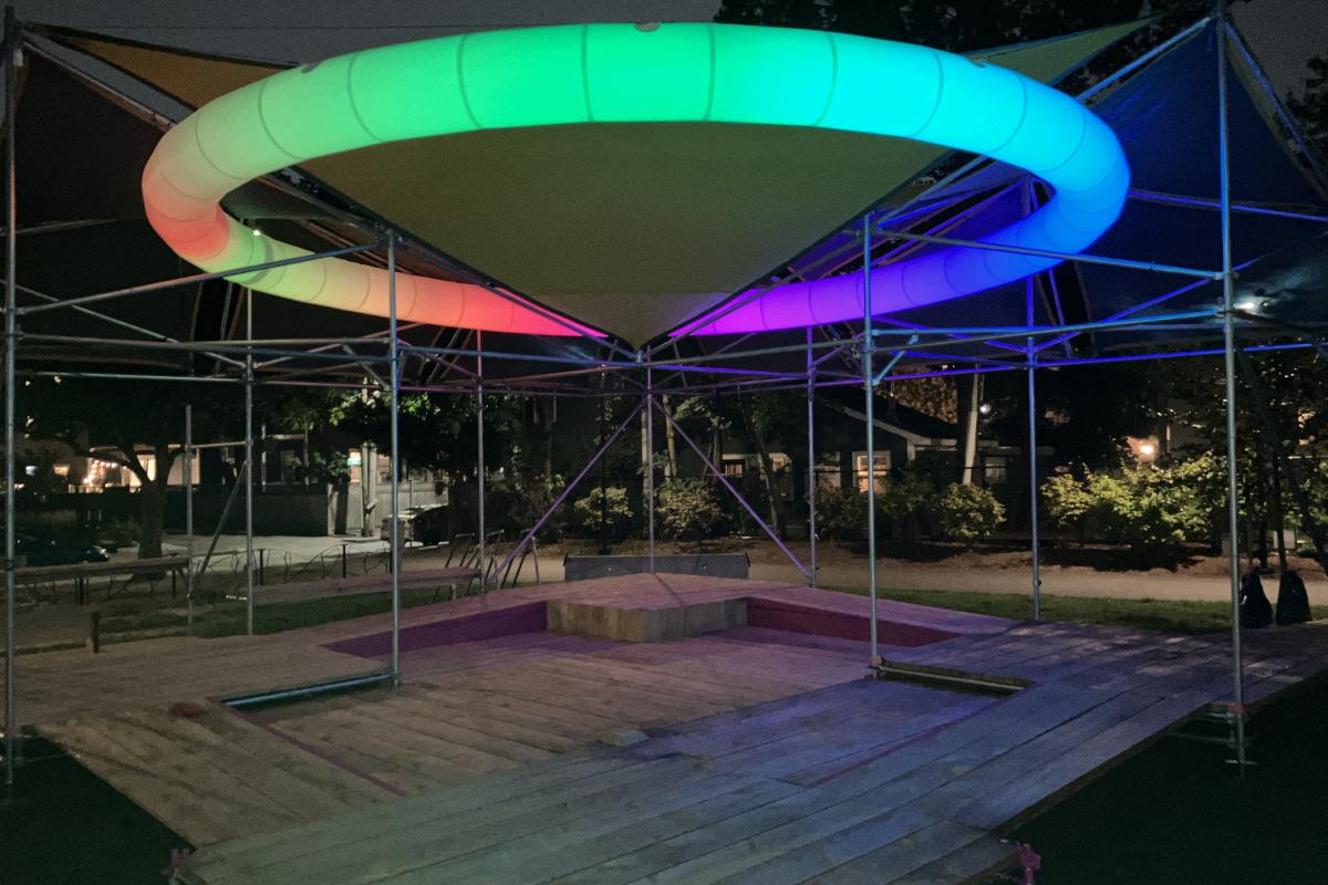 The Shade structure lit up at night. 