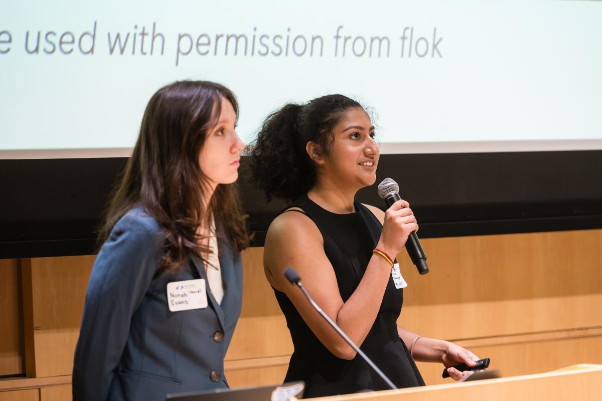 Students presenting slides in packed auditorium 