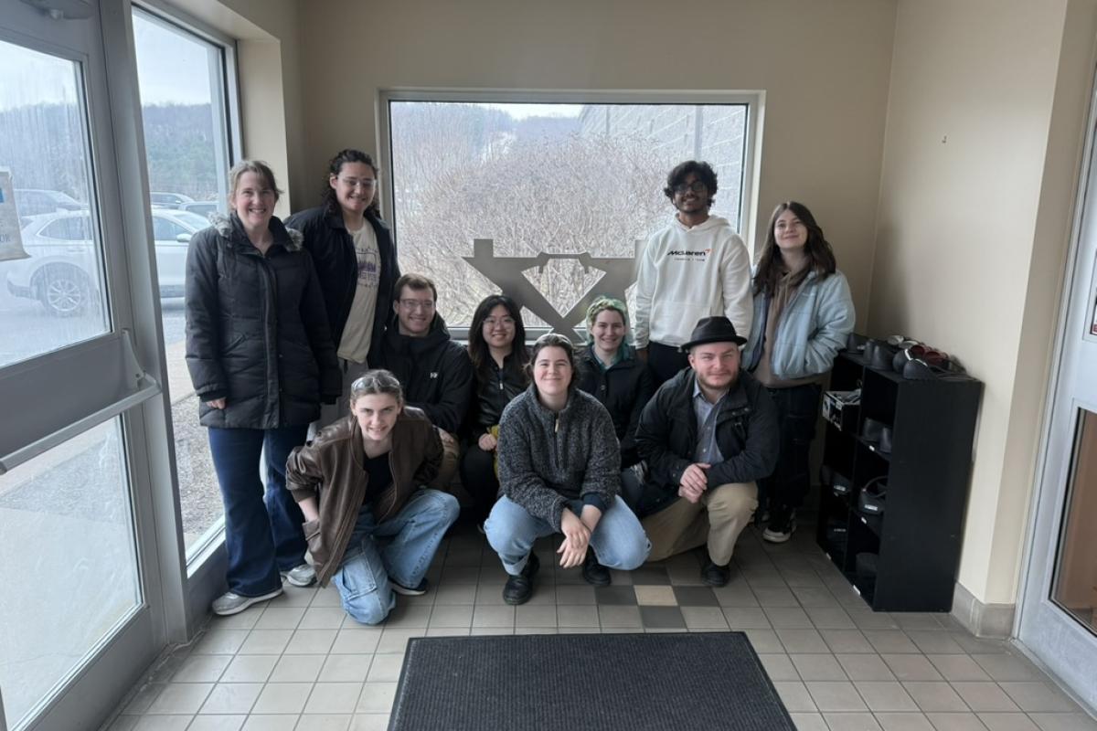 A group a students and an Olin staff member stand in a vestibule at Instron. 
