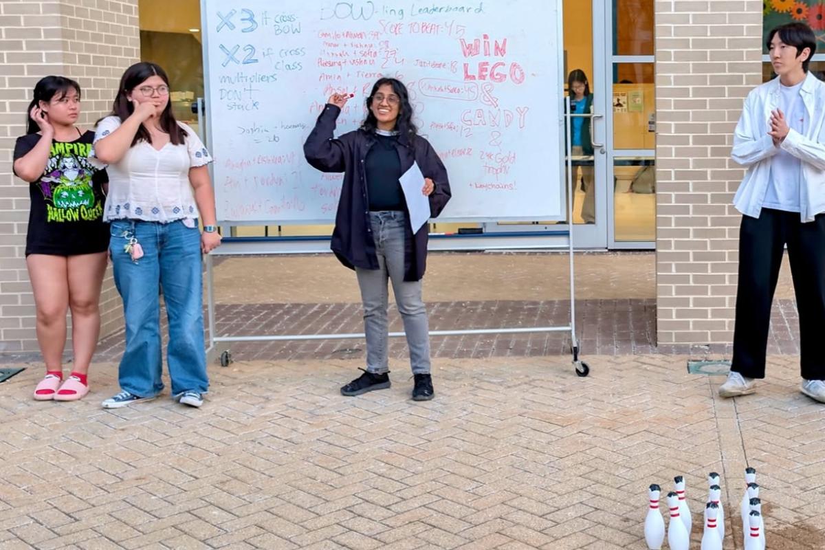 Ameya ’29 stands in front of a white board at the BOW-ling event. 