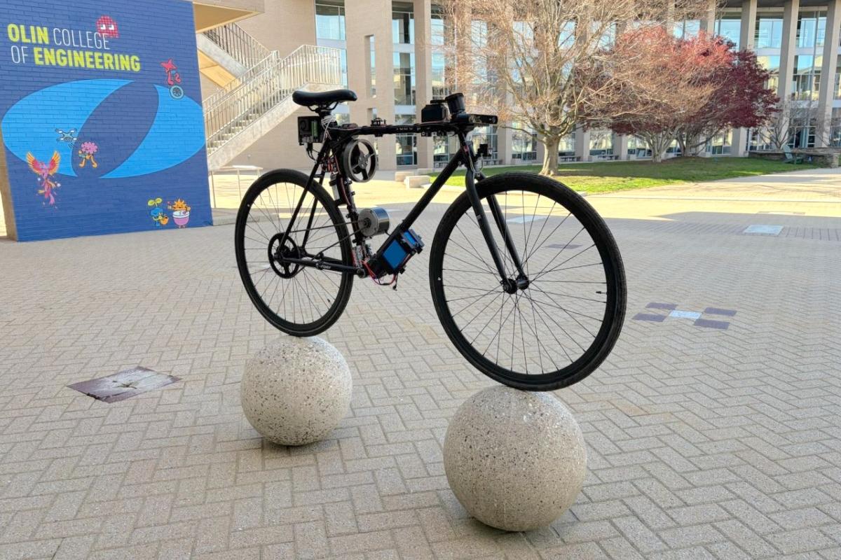 An autonomous self-balancing bicycle is pictured balancing on two stone balls on Olin's campus.