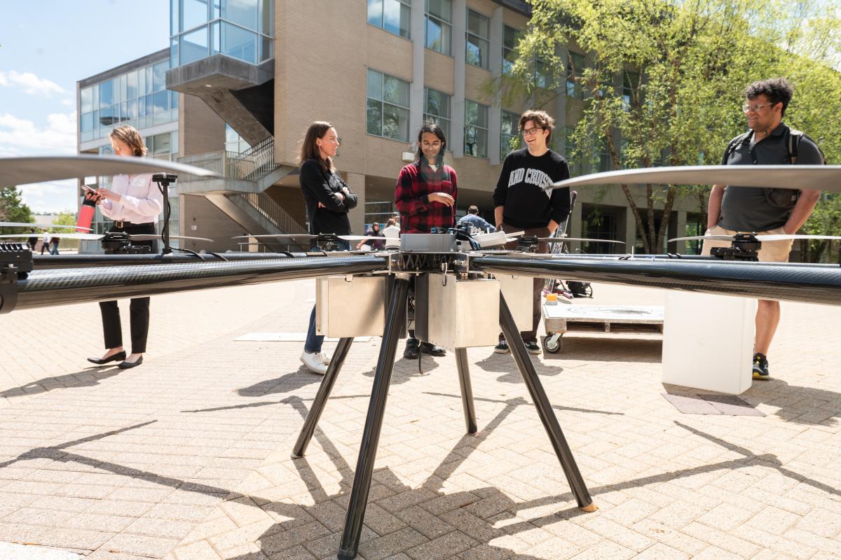 Members of the OCTAL team stand with their firefighting drone at the 2026 Spring Expo alongside Olin Professors.